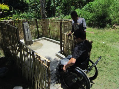 A man using a wheelchair is testing an accessible waterpump, by using the ramp up to the apron.
